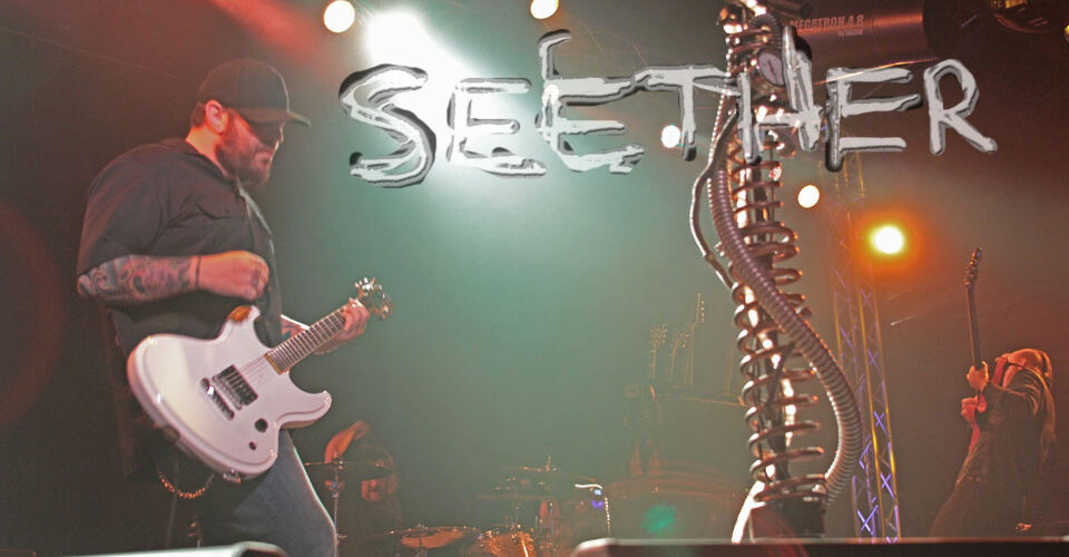 A man playing guitar on stage with the words seether.