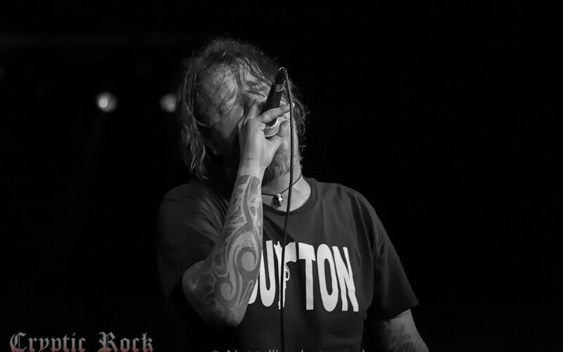 A man with tattoos singing into a microphone.