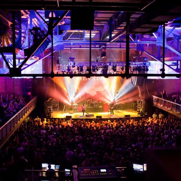 A crowd of people at a concert in a large auditorium.