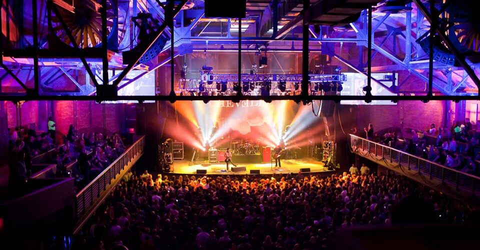 A crowd of people at a concert in a large auditorium.