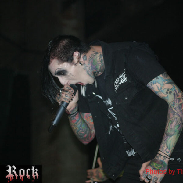 A man with tattoos singing into a microphone.