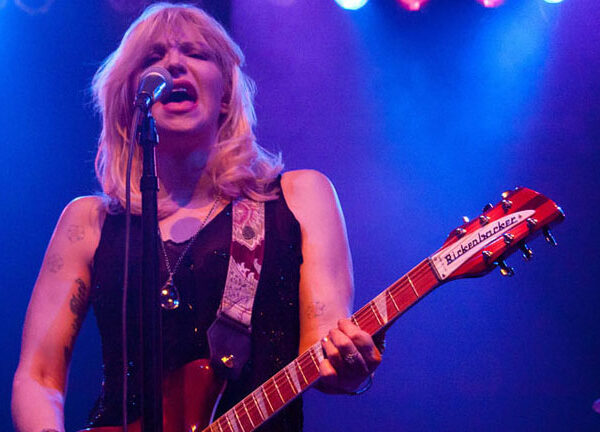 A woman playing a guitar in front of a microphone.