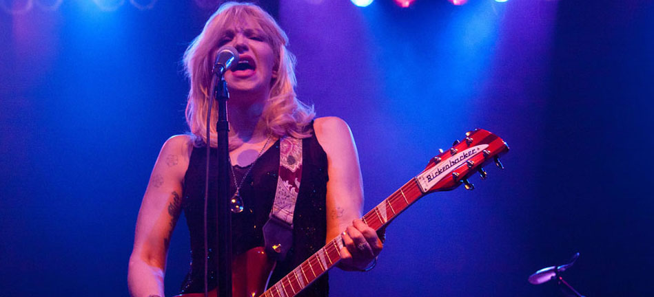 A woman playing a guitar in front of a microphone.