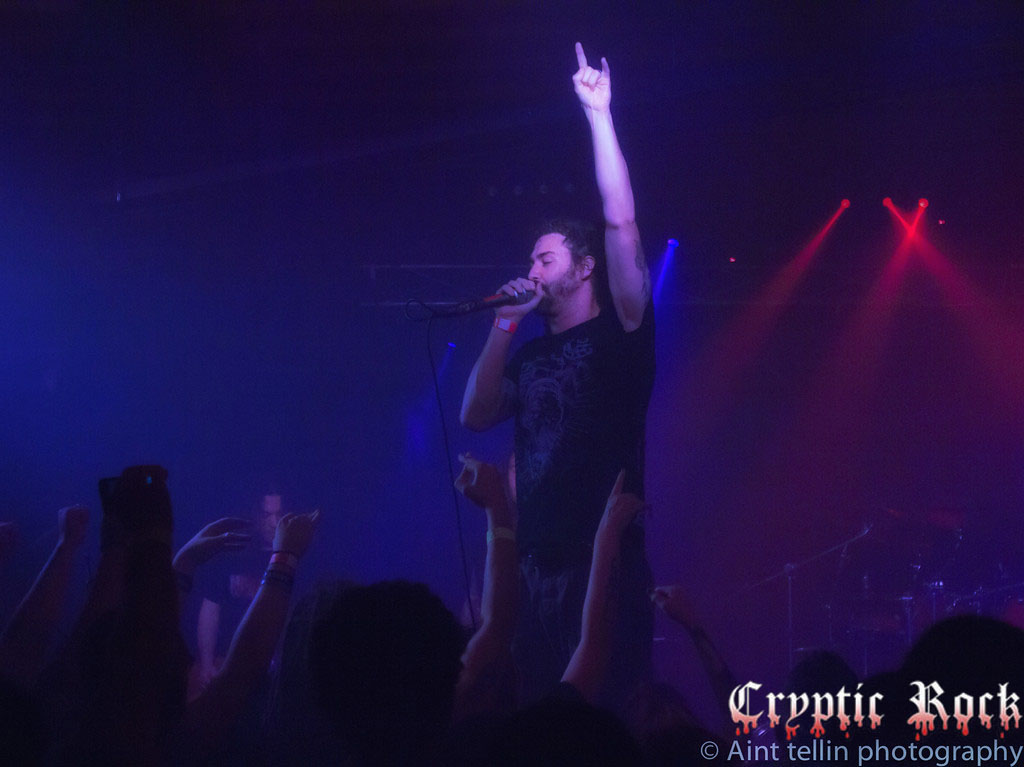 A man on stage with his hands raised in the air.