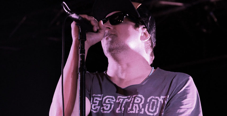 A man in sunglasses singing into a microphone.