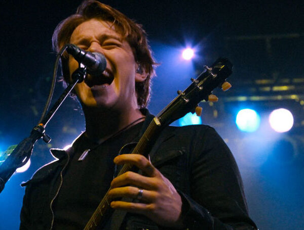 A man singing into a microphone while holding a guitar.