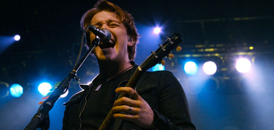 A man singing into a microphone while holding a guitar.