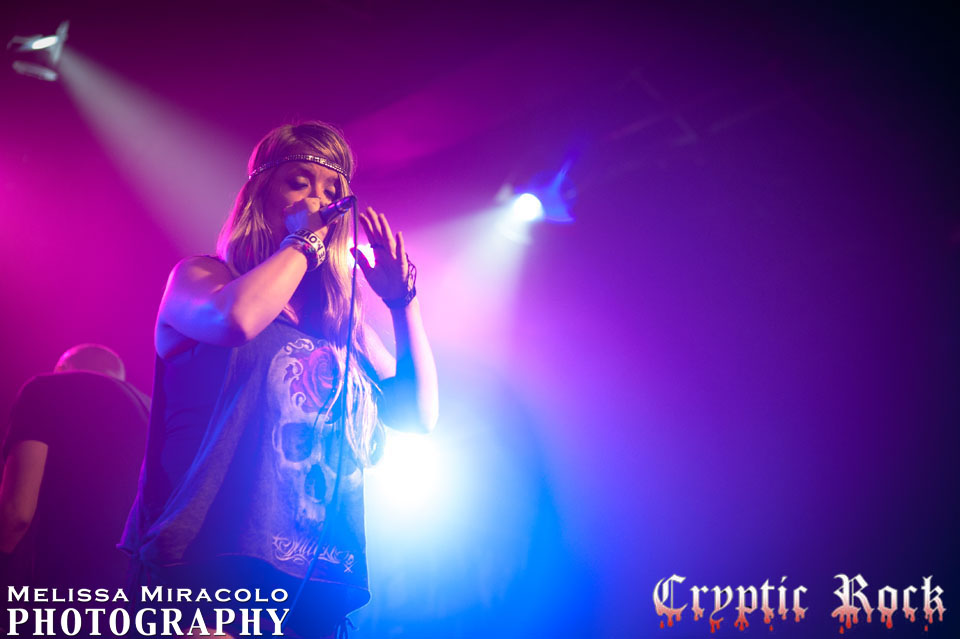 A woman singing into a microphone at a concert.