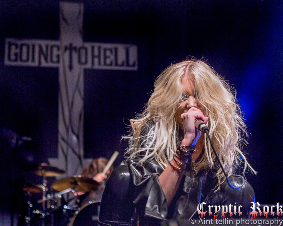 A woman with long hair singing into a microphone.