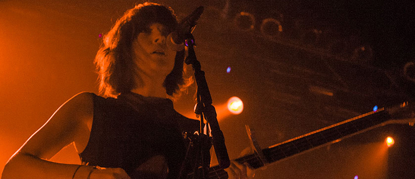 A woman playing a guitar in front of a microphone.