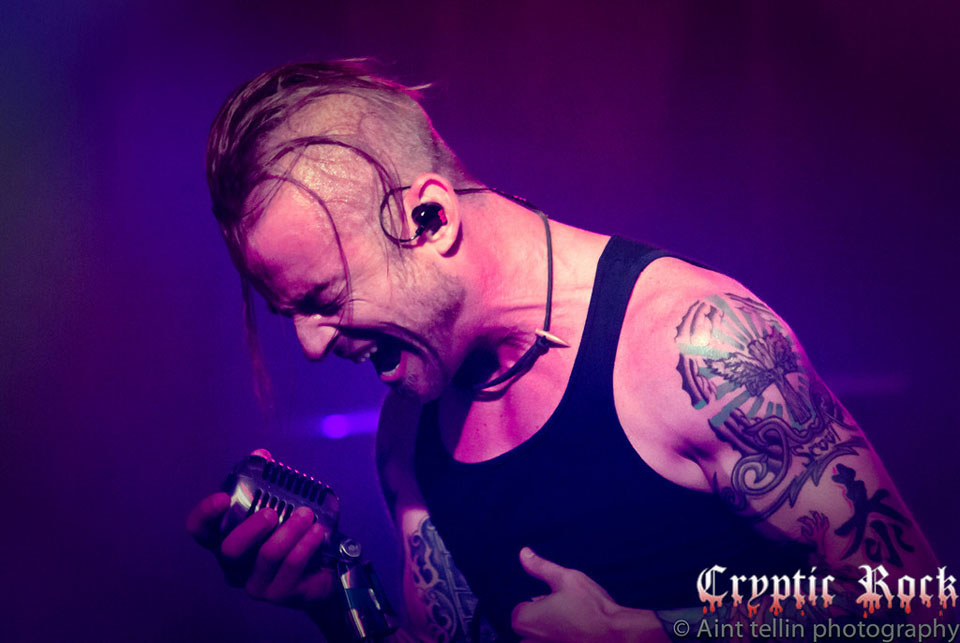 A man with tattoos singing into a microphone.