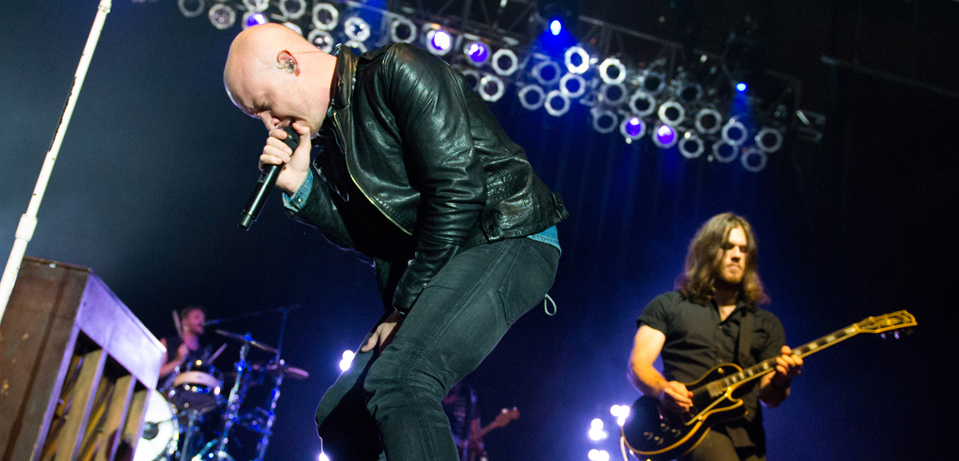 A man in a leather jacket singing on stage.