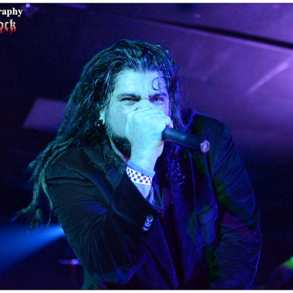 A man with dreadlocks singing into a microphone.