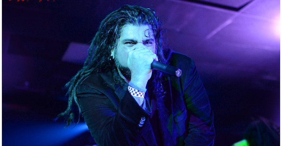 A man with dreadlocks singing into a microphone.