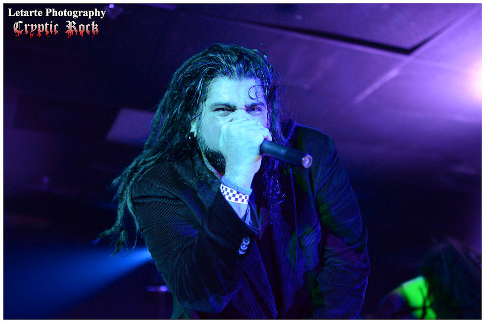 A man with dreadlocks singing into a microphone.