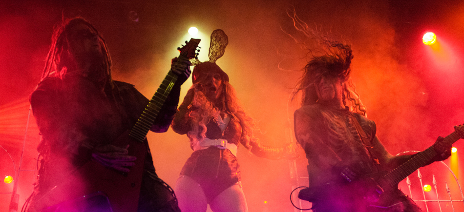 A group of people with long hair and guitars on stage.