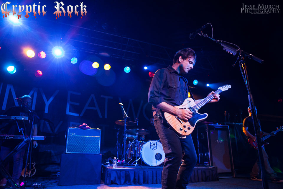 A man playing guitar on stage at a concert.