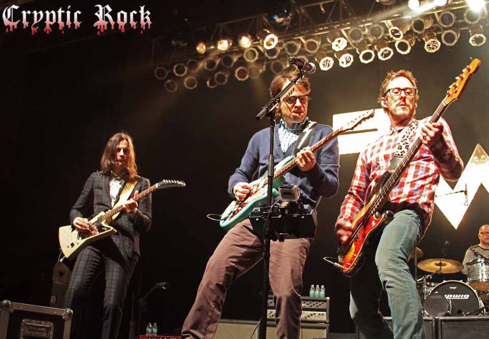 A group of men playing guitars on stage.