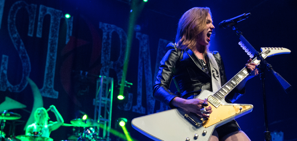 A woman playing an electric guitar on stage.