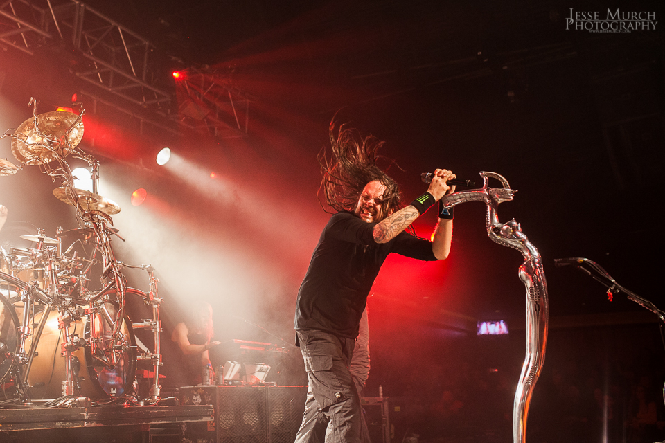 A man with long hair on stage holding a microphone.