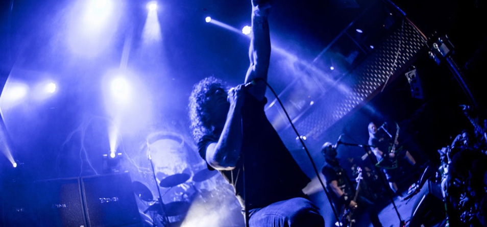 A man performing on stage in front of blue lights.